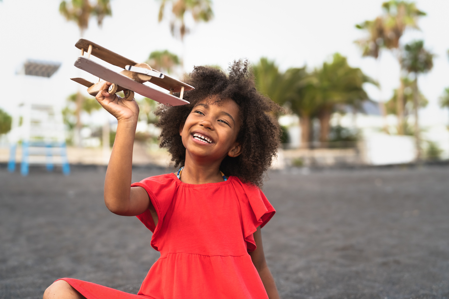 Afro Child Playing with Wood Toy Airplane on the Beach 